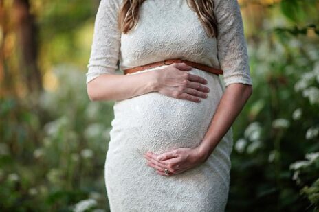 Woman holds pregnant belly